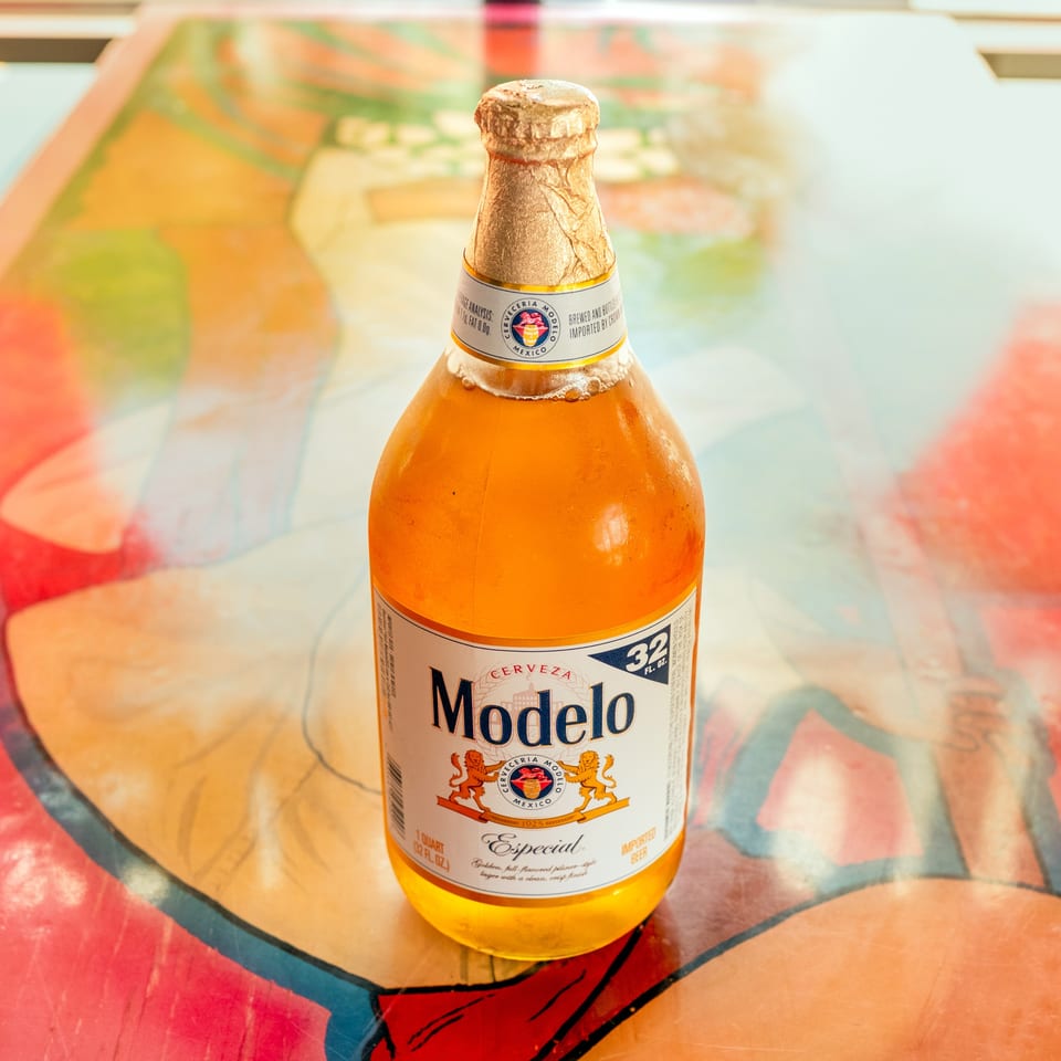 A Modelo Especial beer bottle stands on a colorful, abstract patterned surface.