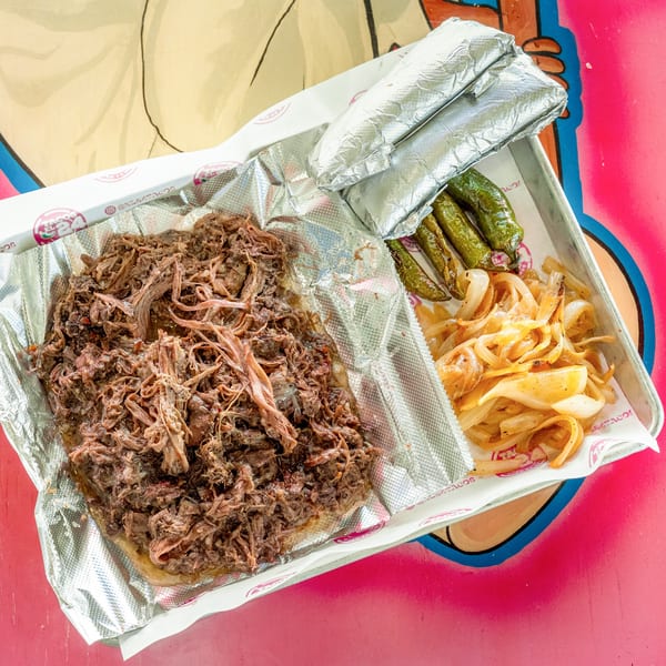 Shredded beef, grilled onions, and green peppers on a foil-lined tray, with two foil-wrapped items.